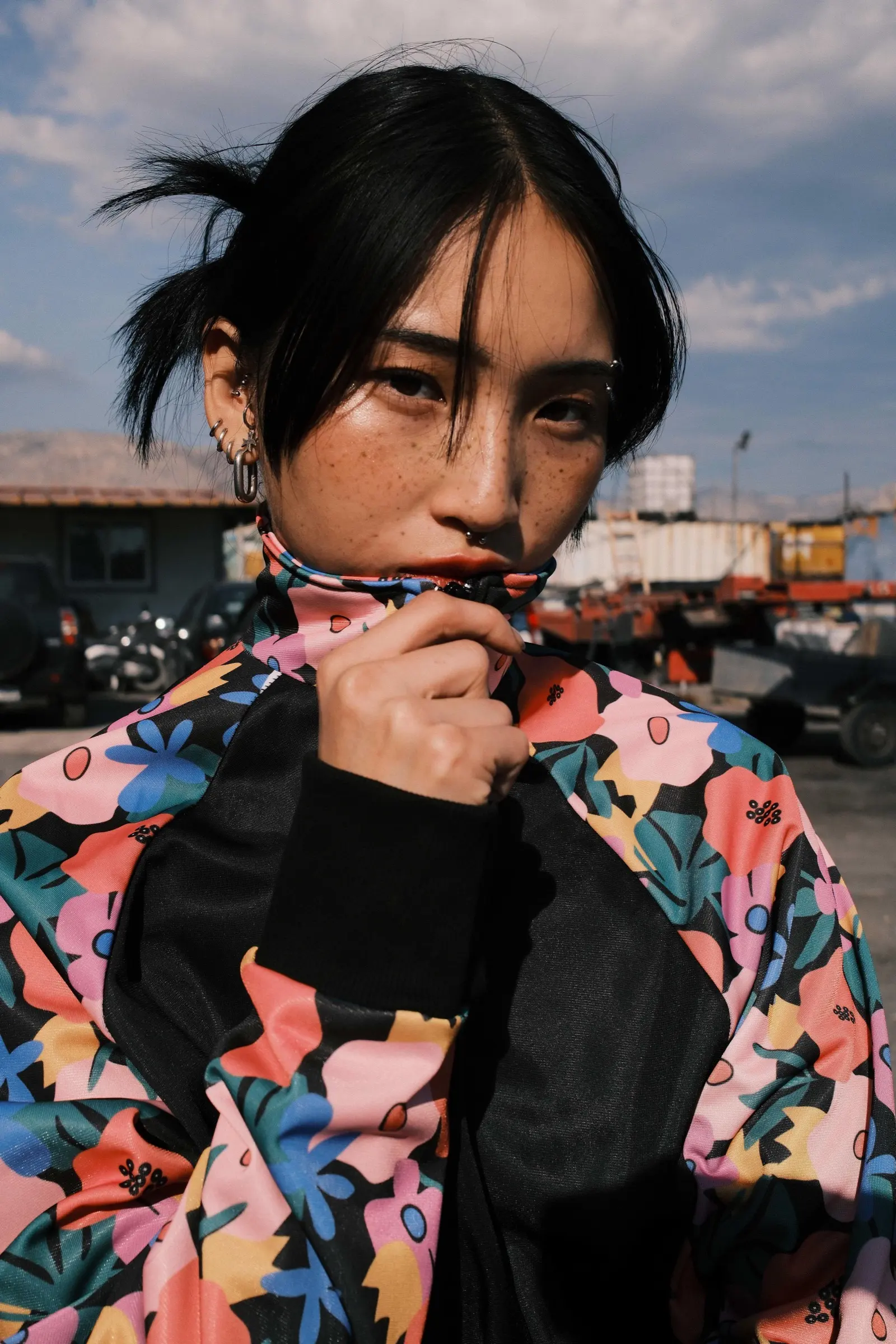 Model holding the high collar of a floral track jacket