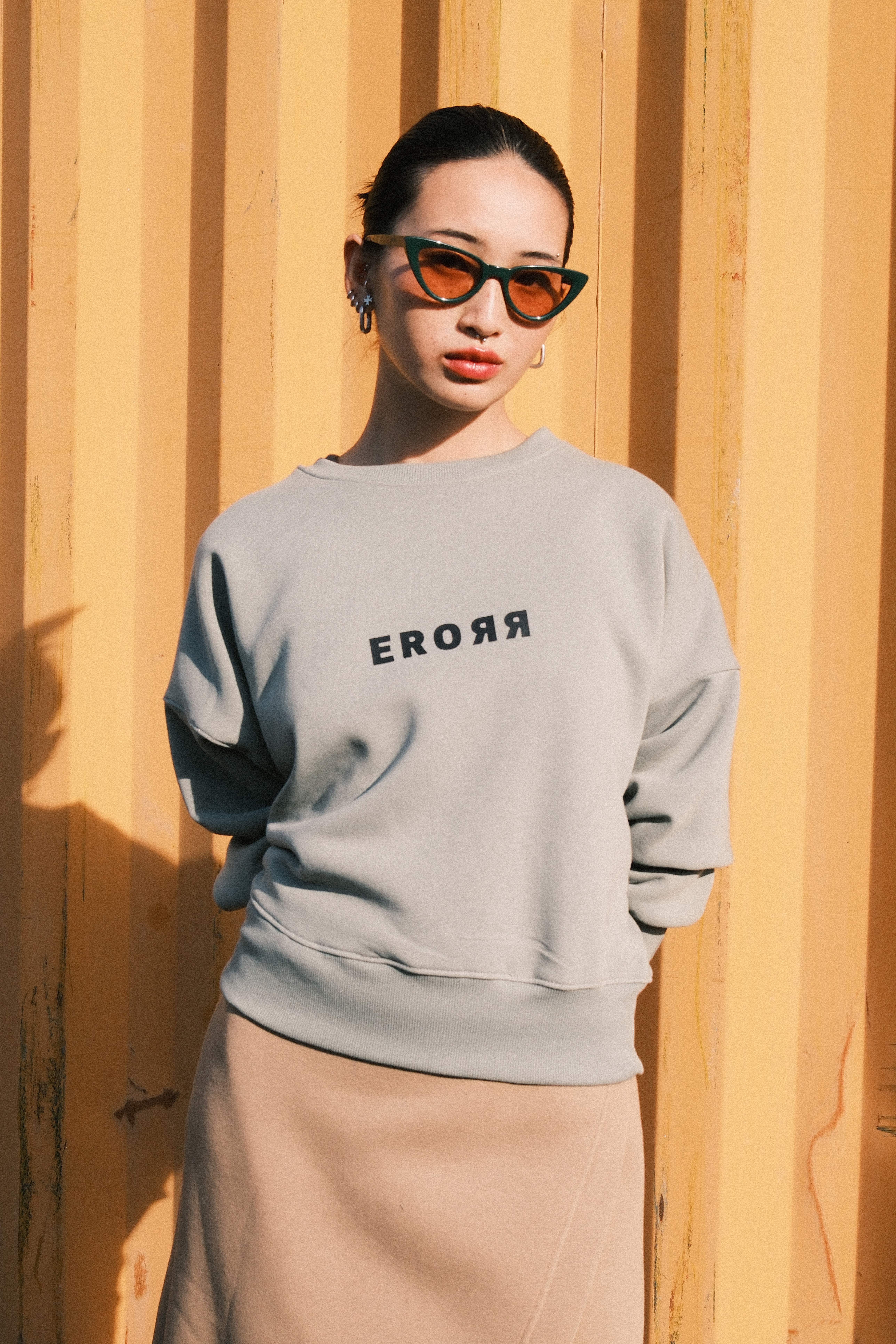 Model leaning on a wall in a black sweatshirt with a colourful doodle print