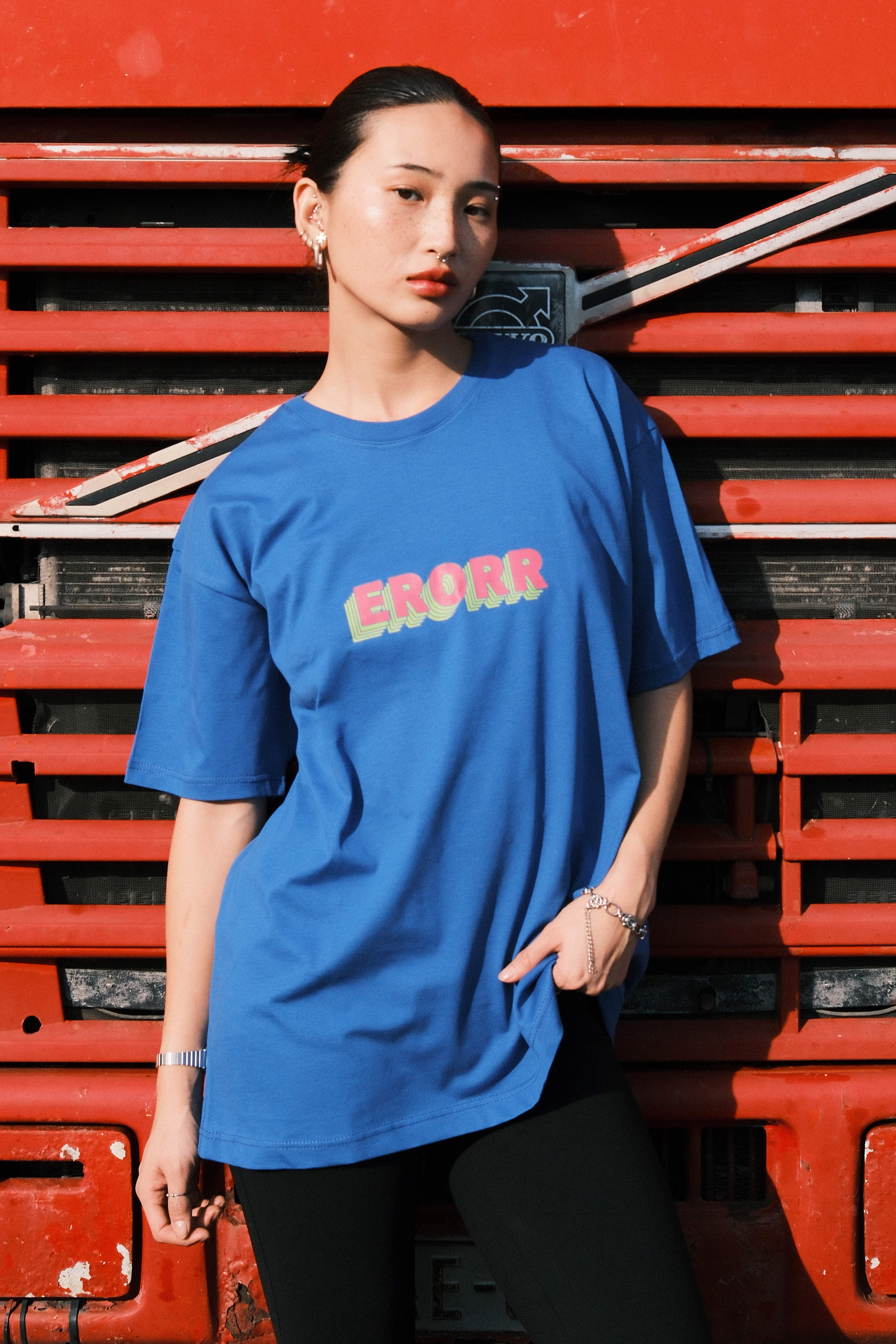Model pulling a red MUSE logo tee up over her face