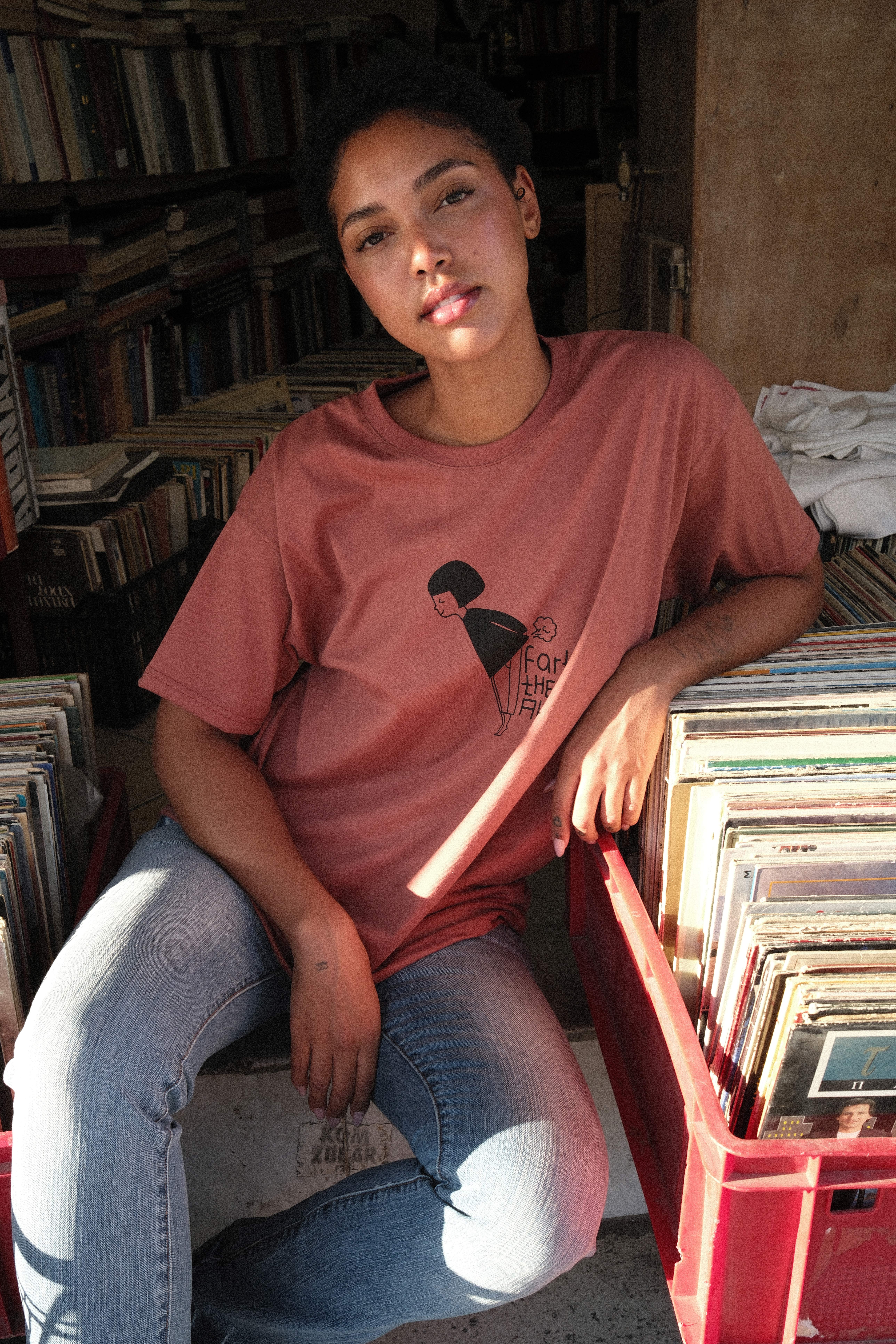 Model pulling a red MUSE logo tee up over her face